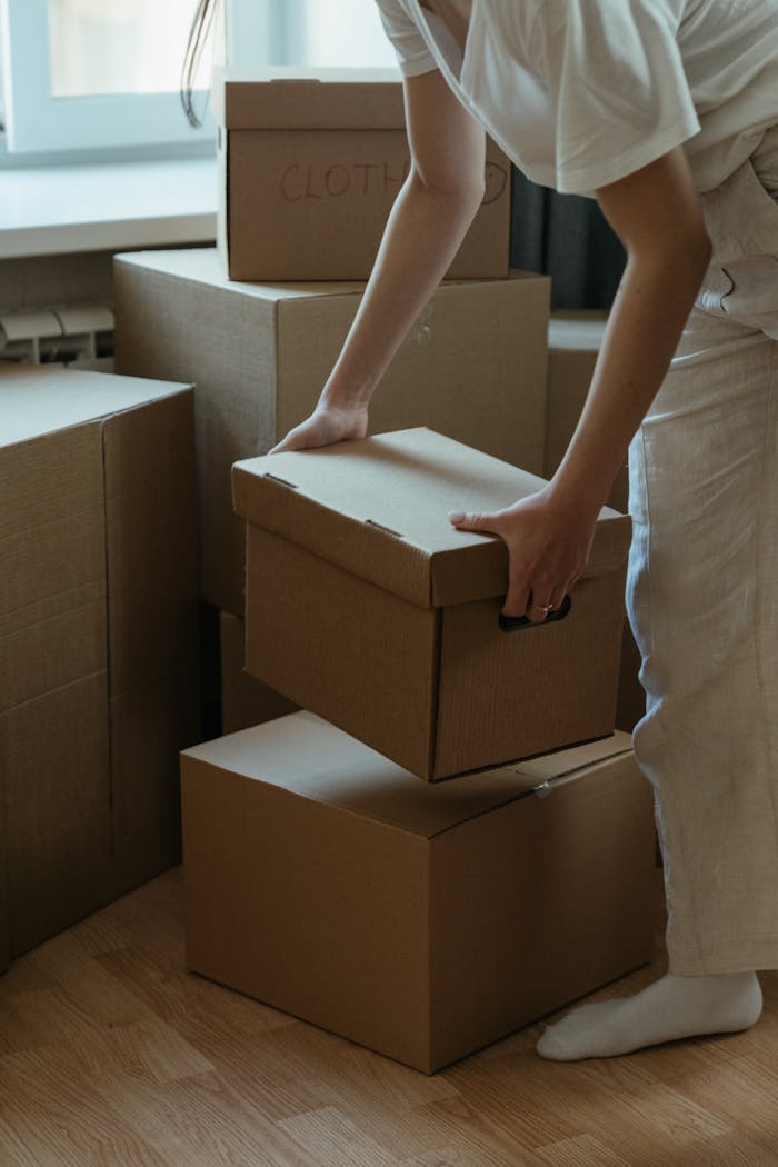 creative-03 A woman packing cardboard boxes in her new apartment, symbolizing moving and relocation.